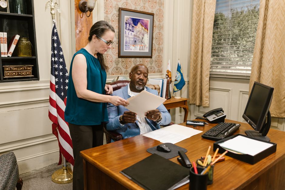 An immigration attorney reviewing documents with a client in a professional office setting - Green card application help
